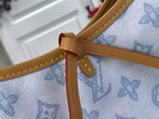 Tan leather strap attachment with red accent underlay on light blue monogram canvas