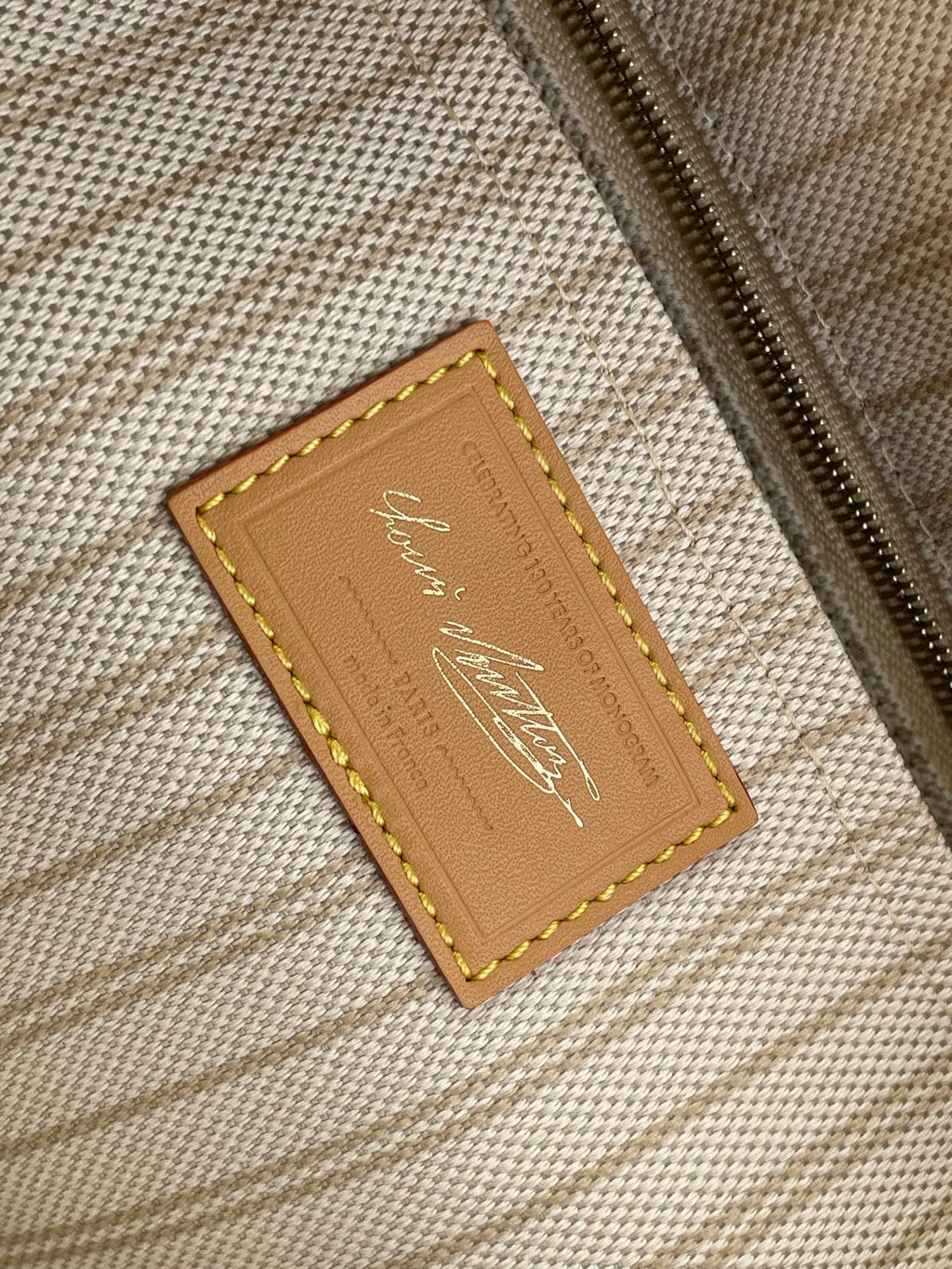 Tan leather interior label with gold logo on beige woven lining