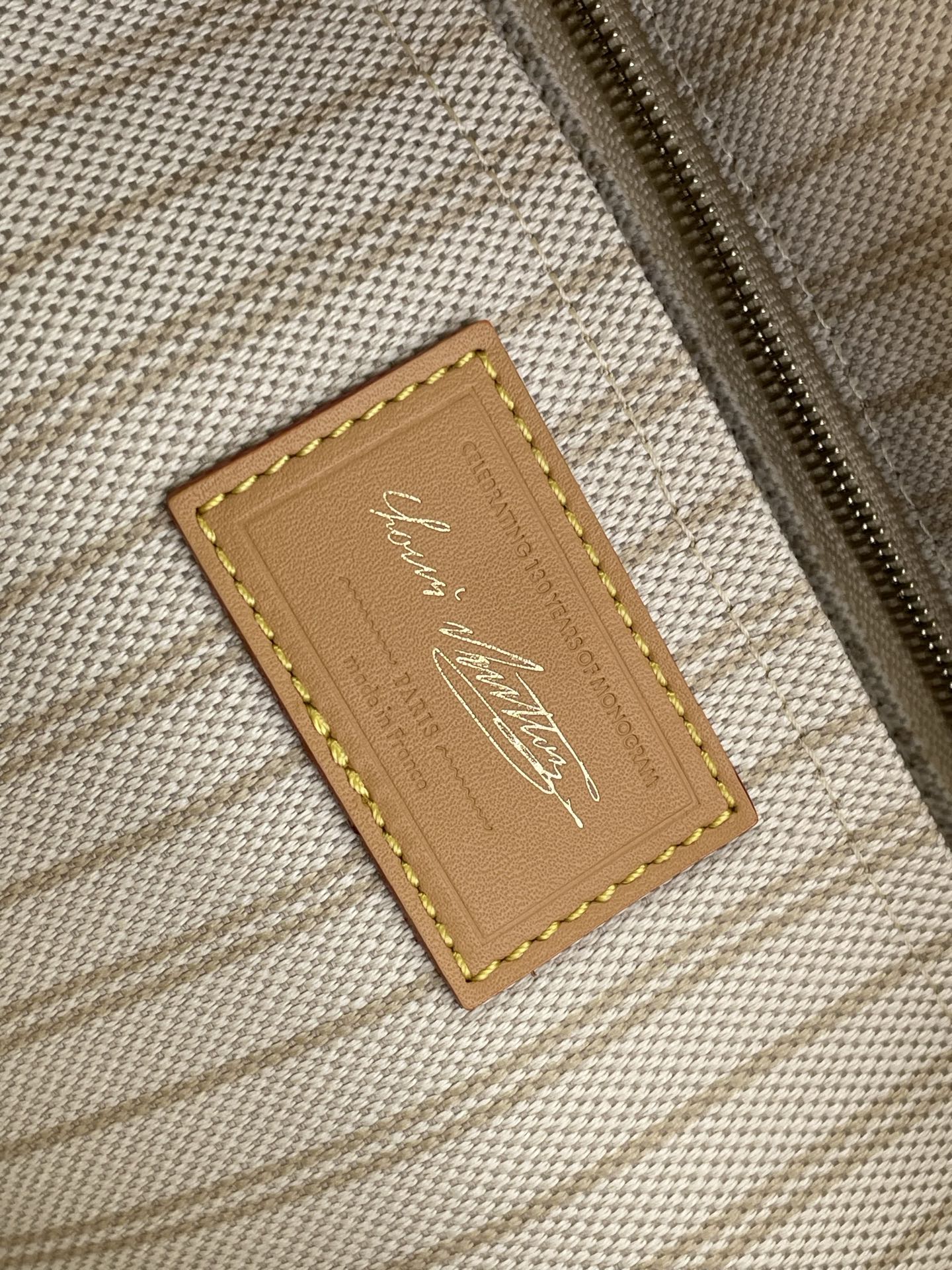 Tan leather interior label with gold logo on beige woven lining
