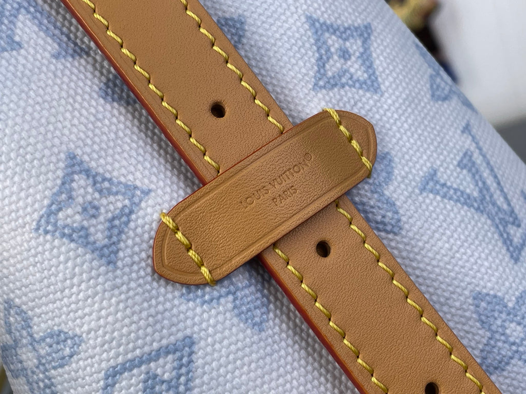 Tan leather strap with stitched edge and rivet holes on light blue monogram canvas