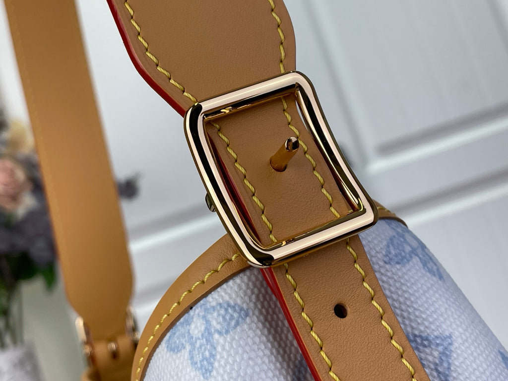 Gold buckle and tan leather strap with stitched edge on blue monogram canvas