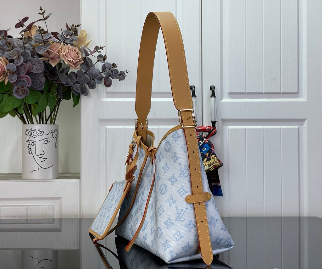 Hobo bag with tan shoulder strap and light blue monogram canvas, front view