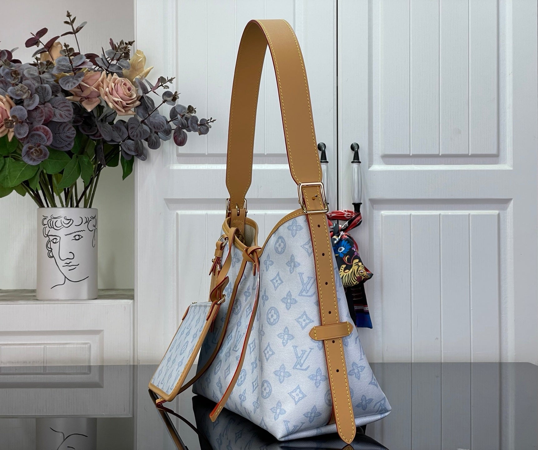 Hobo bag with tan shoulder strap and light blue monogram canvas, front view