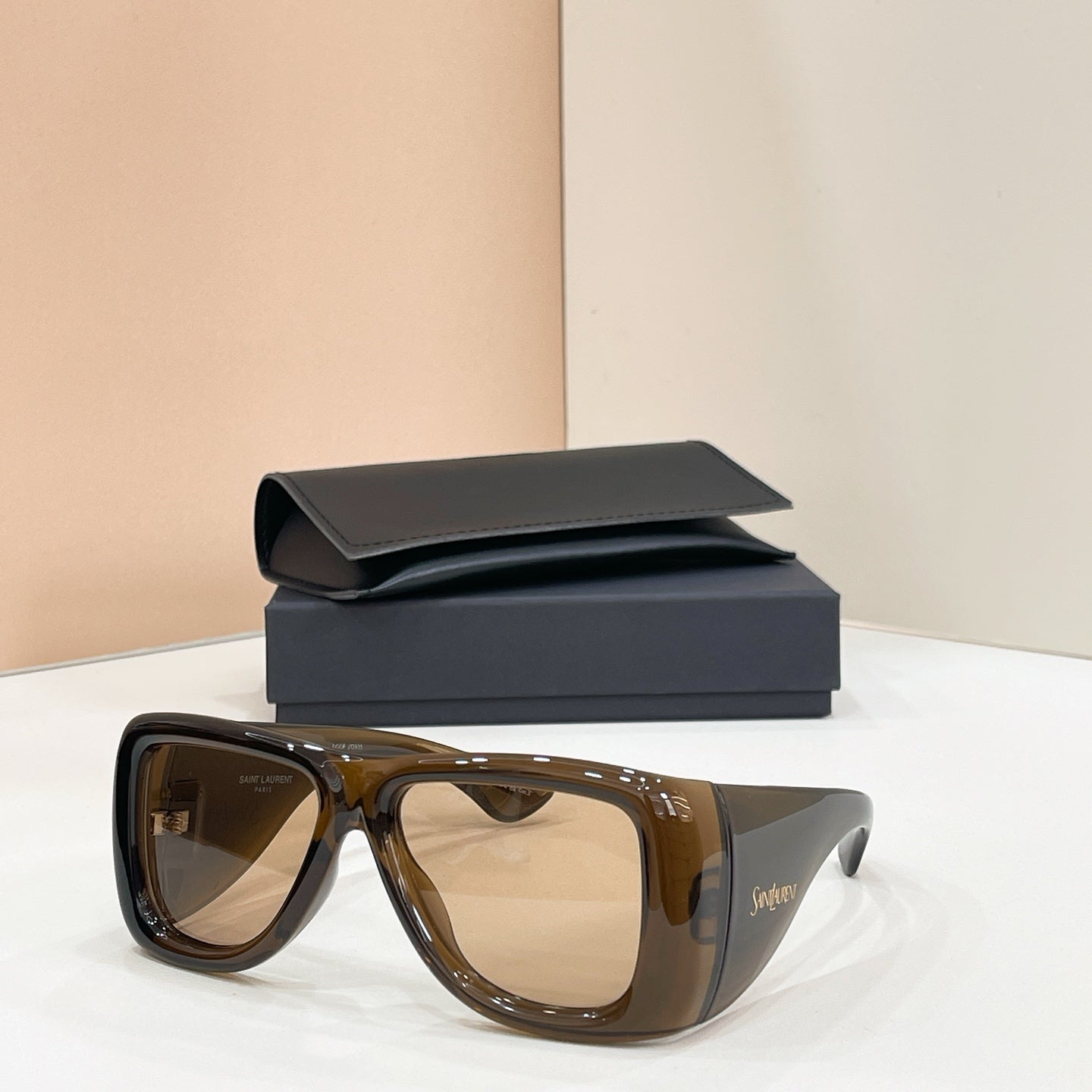 Sunglasses with brown lenses and dark tortoise frames, with case behind