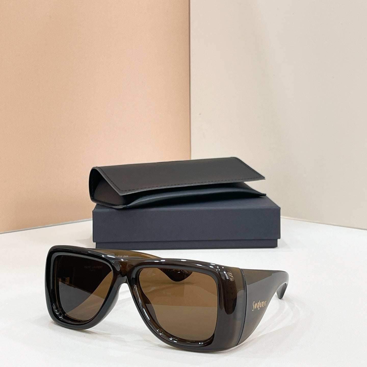 Sunglasses with dark lenses and dark tortoise frames, with case behind