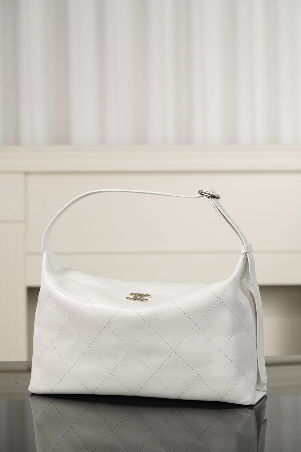 Chanel white quilted hobo shoulder bag with curved top handle and dangling strap tab