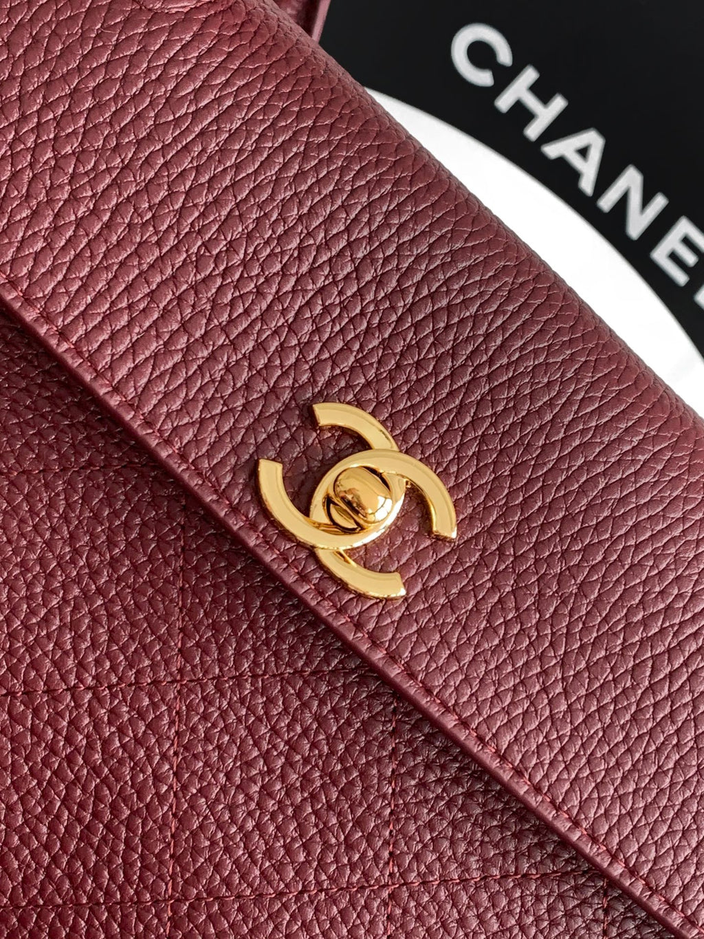 Chanel handbag front flap with burgundy textured leather and gold interlocking logo