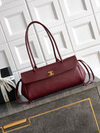 Chanel handbag in burgundy with top handles, shoulder strap, and gold logo hardware