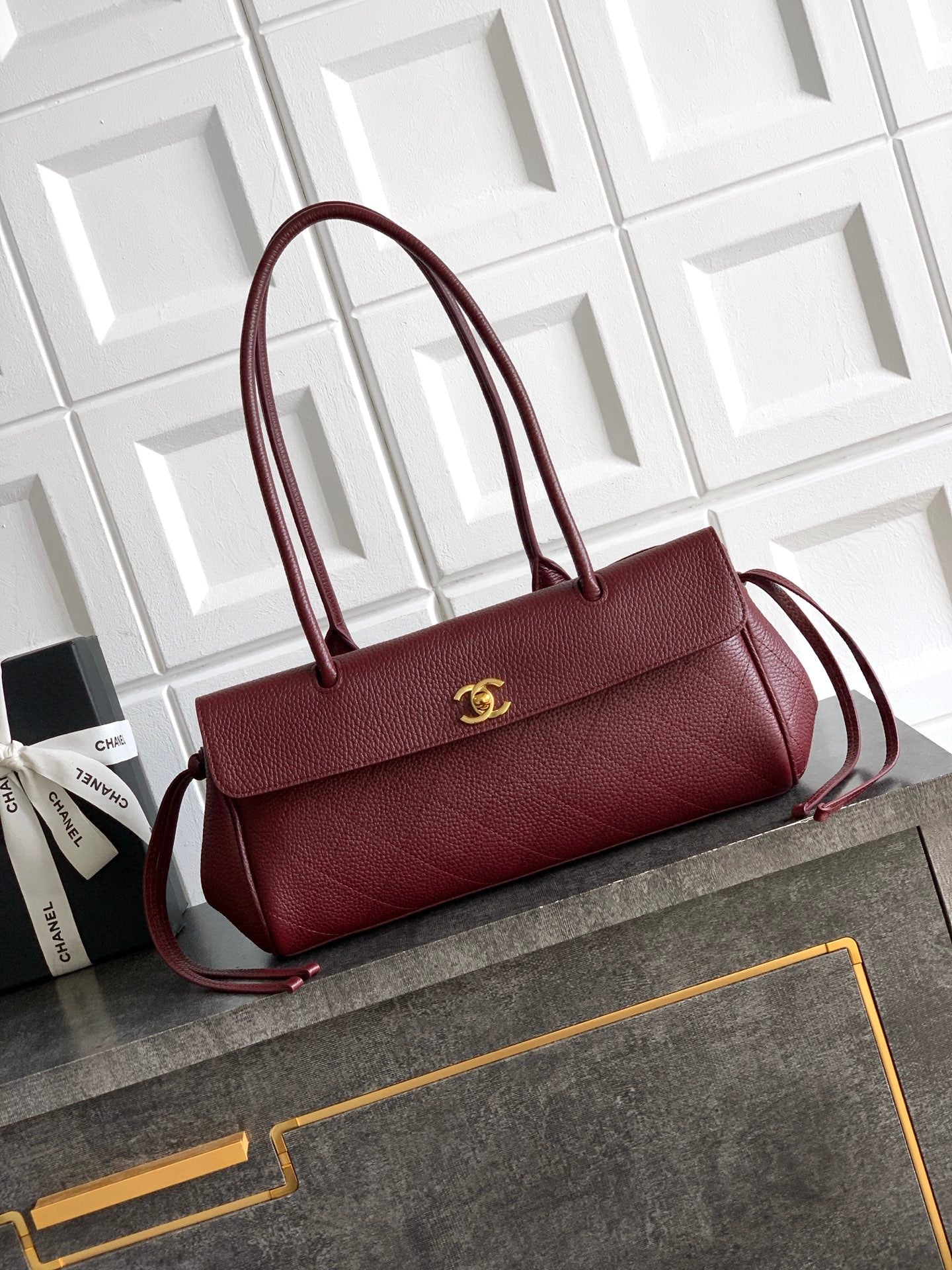 Chanel handbag in burgundy with top handles, shoulder strap, and gold logo hardware