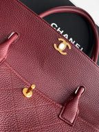 Chanel handbag exterior with burgundy textured leather, gold logo, and front accent ring