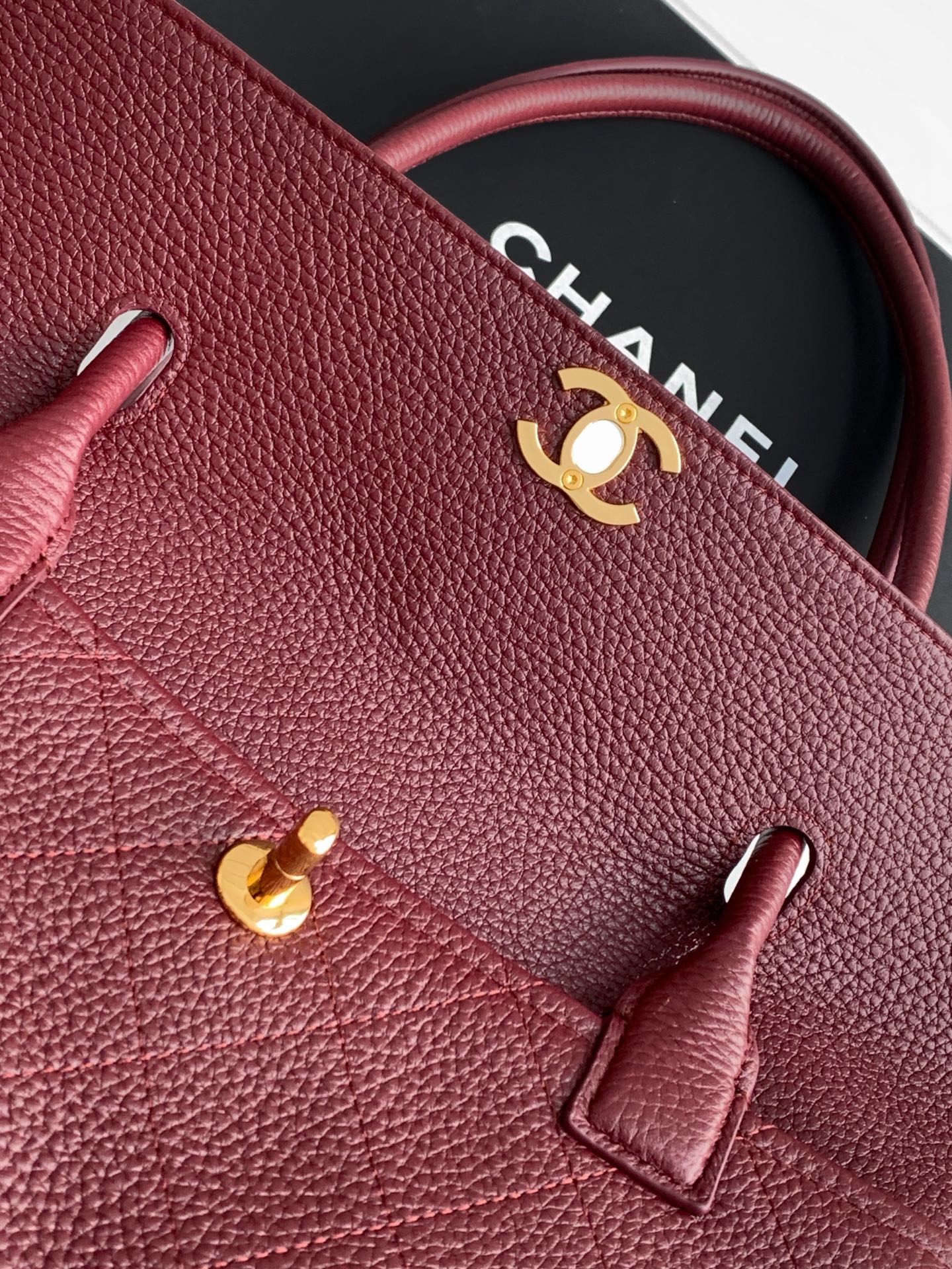 Chanel handbag exterior with burgundy textured leather, gold logo, and front accent ring