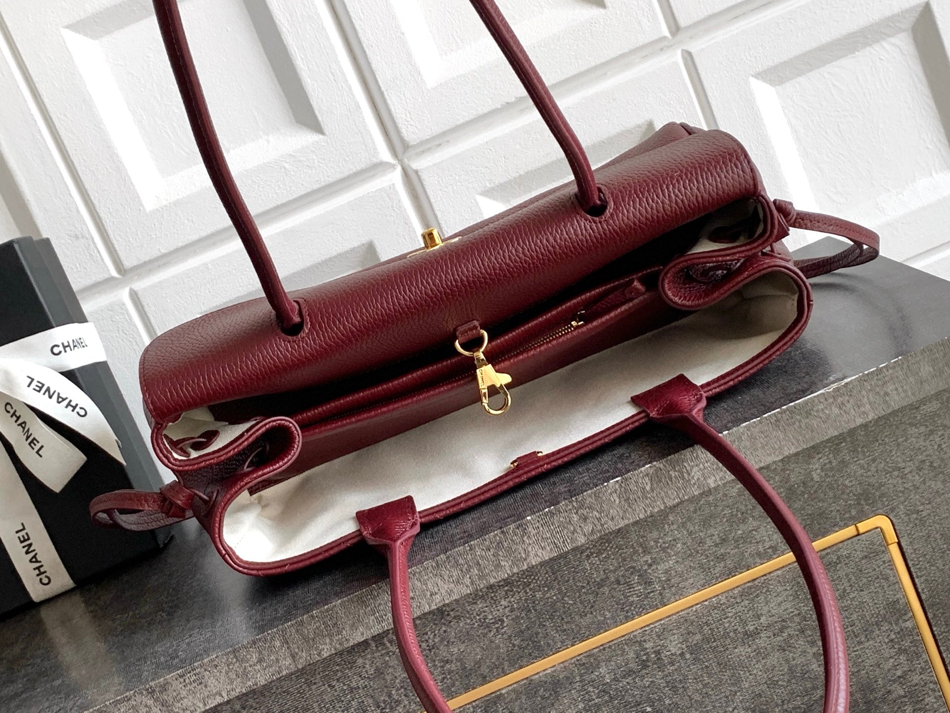 Chanel burgundy shoulder bag laid flat with strap and gold zipper pull hardware