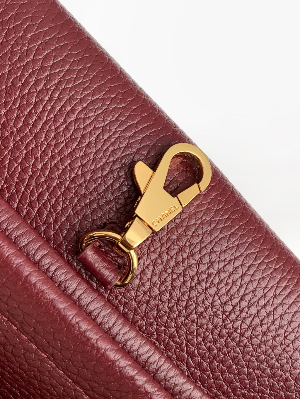 Chanel handbag clasp detail on burgundy textured leather with gold hardware