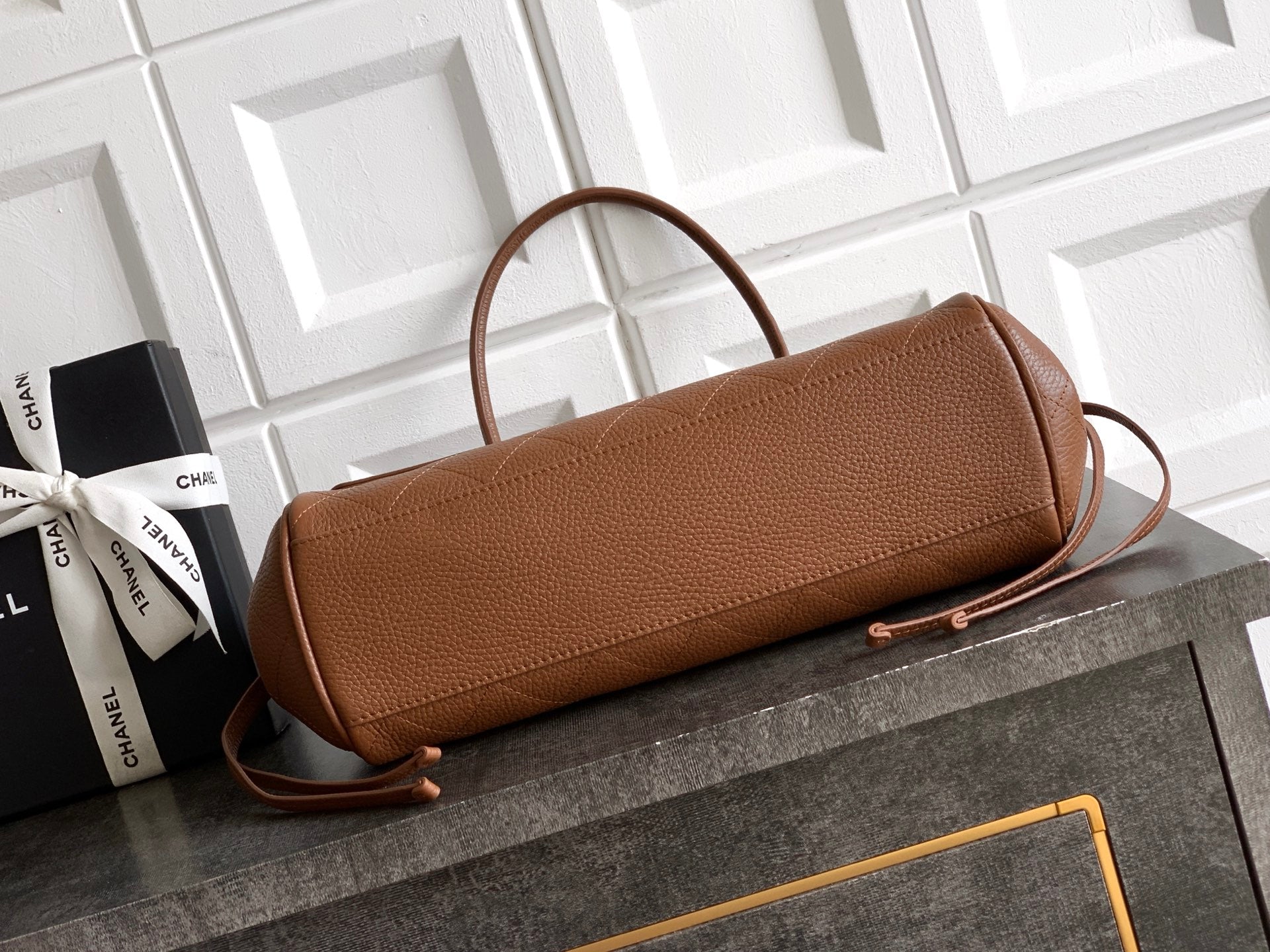 Chanel brown leather handbag with top handle and front flap, gold clasp hardware