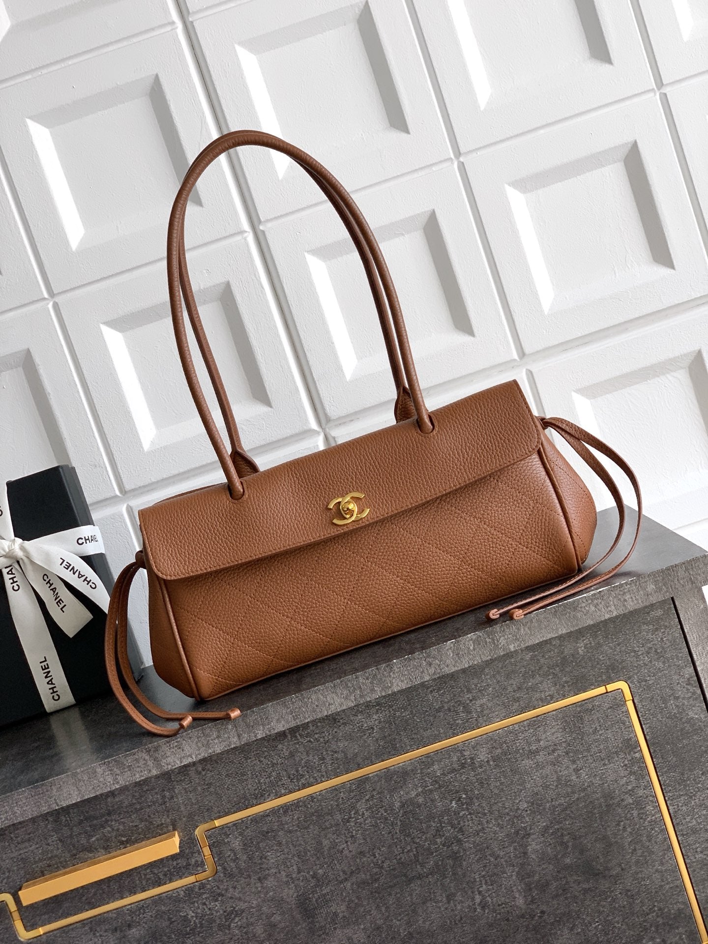 Chanel brown leather handbag with top handles, front flap, and gold logo
