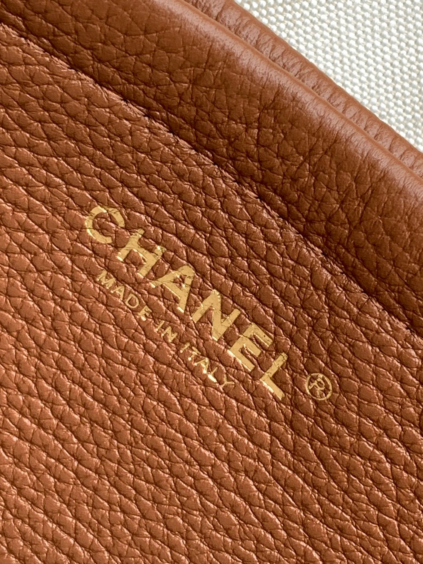 Chanel brown leather bag with embossed logo text and textured grain