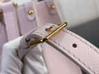 Light pink leather bag hinge with gold-toned metal bar and rivet accents