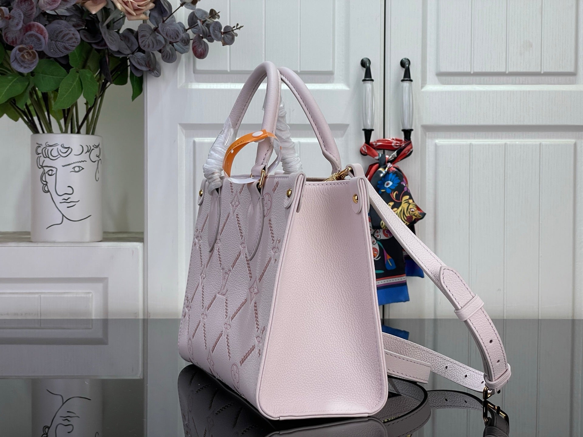 Light pink structured tote bag with top handles, shoulder strap, and gold hardware