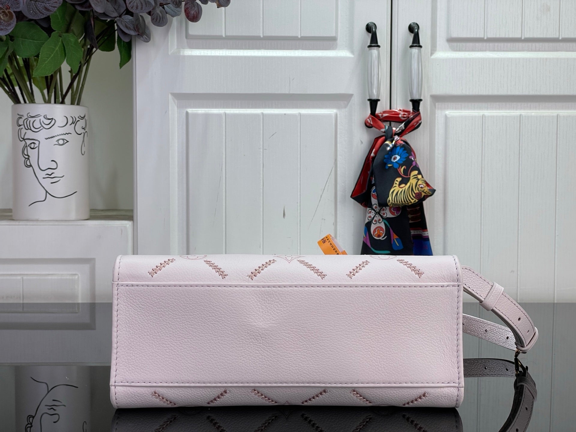 Light pink leather handbag with top flap and gold-tone hardware, plus crossbody strap