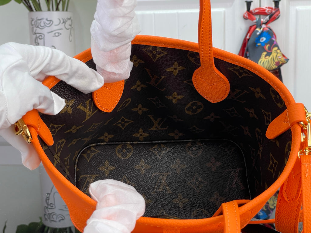 Orange-trimmed interior of monogram canvas bag with open top and handles