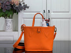 Orange leather-look tote bag with dual handles and gold side hardware