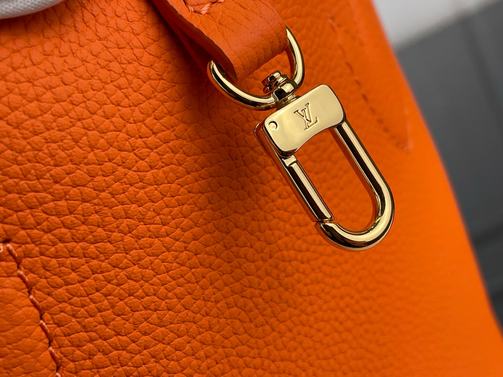 Orange leather bag close-up of gold U-shaped clasp hardware