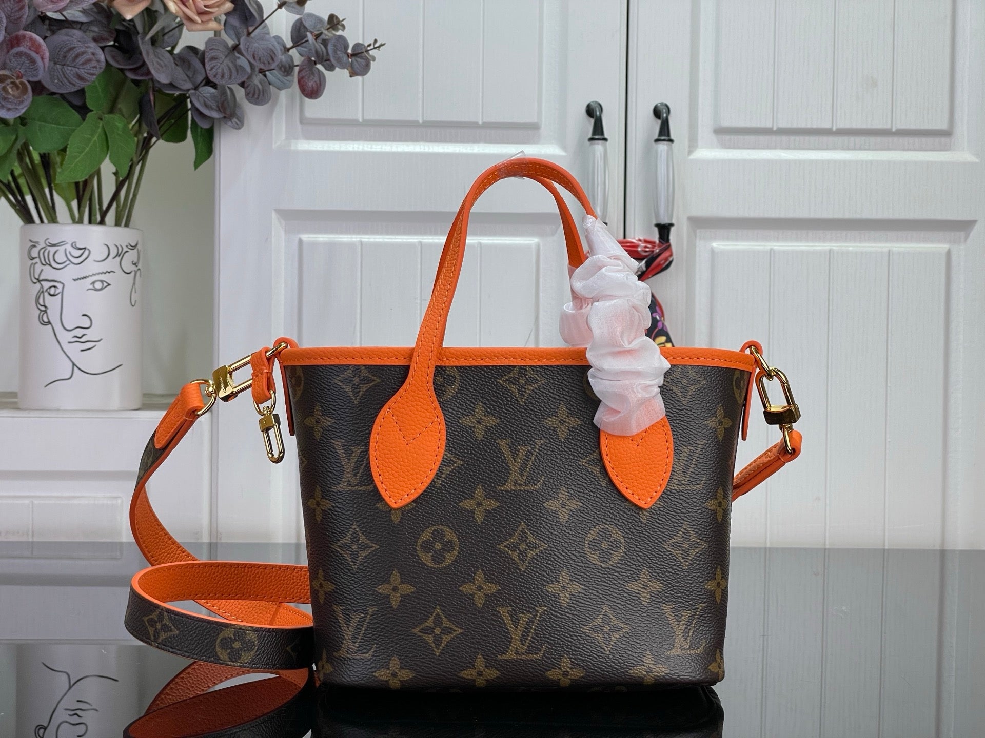 Louis Vuitton monogram handbag with orange top handles and side straps, front view