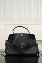 Chanel handbag front view in dark leather, flap cover, small gold top clasp, short handles