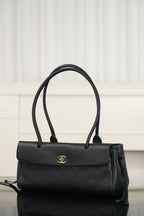 Chanel handbag with dark leather flap, gold logo emblem, top handles and shoulder strap