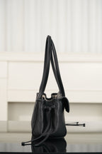 Chanel mini handbag on its side, dark leather, top handle and adjustable shoulder strap