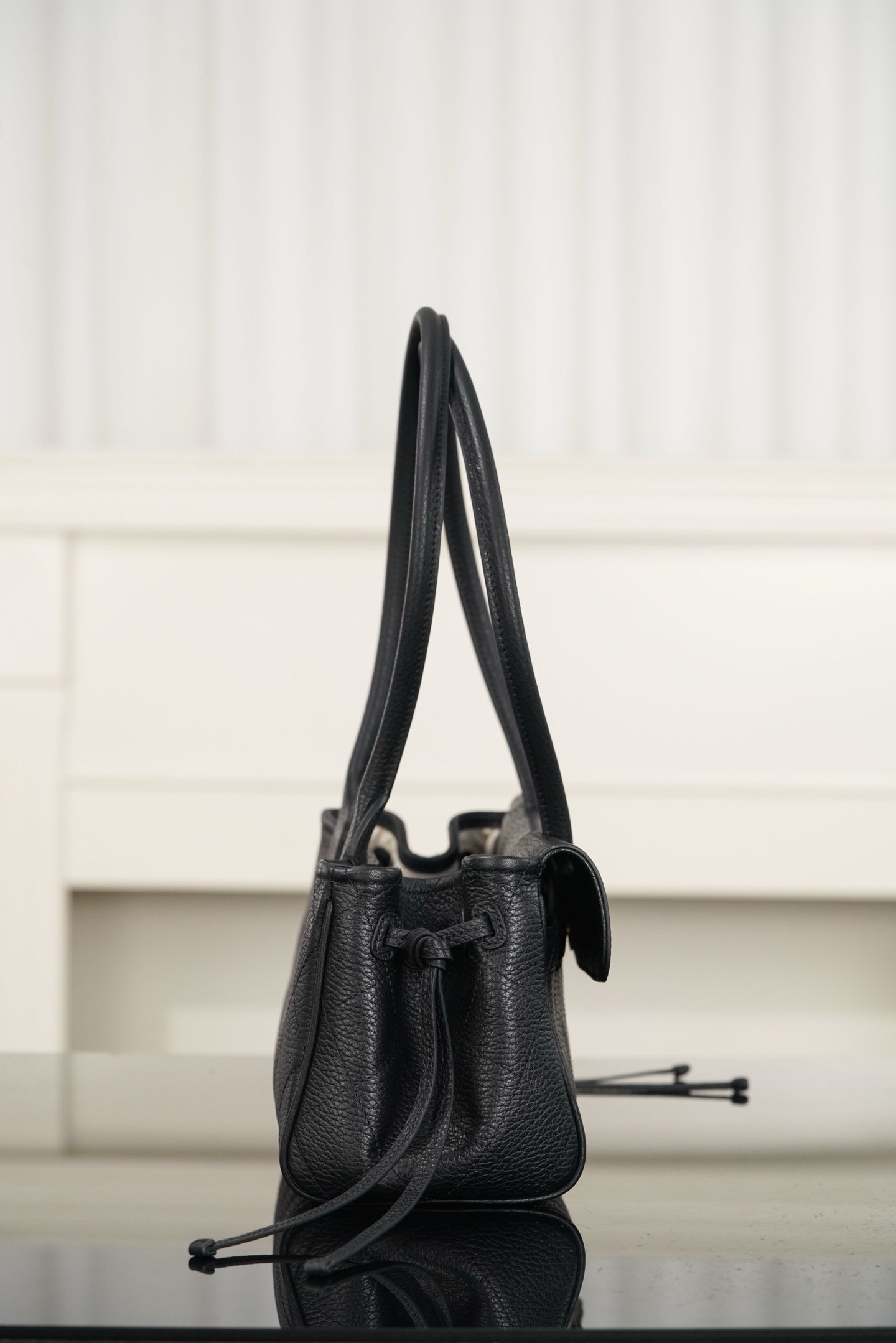 Chanel mini handbag on its side, dark leather, top handle and adjustable shoulder strap