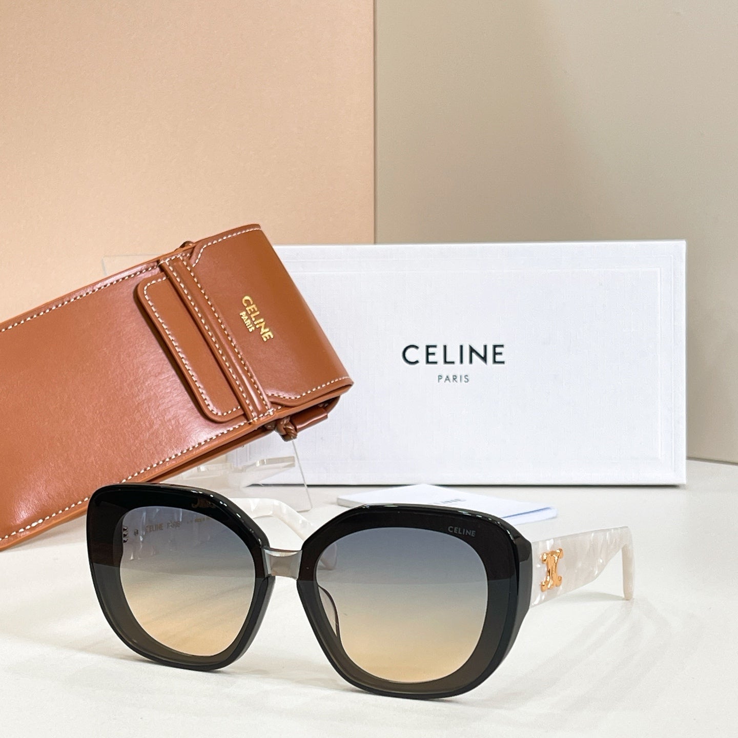 Black round sunglasses with warm gradient lenses and gold-tone side logo