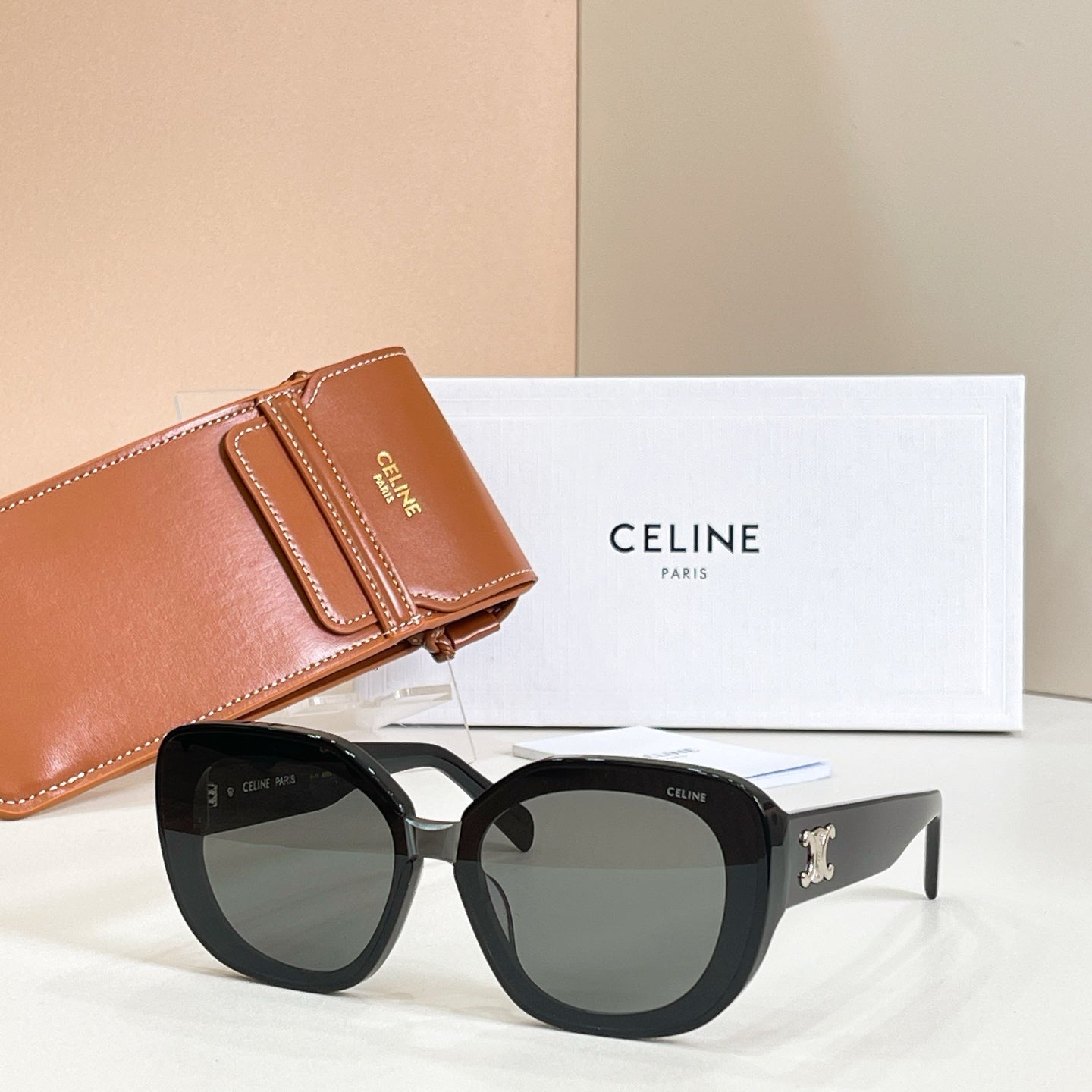 Black round sunglasses with tinted lenses and gold logo on the side arms
