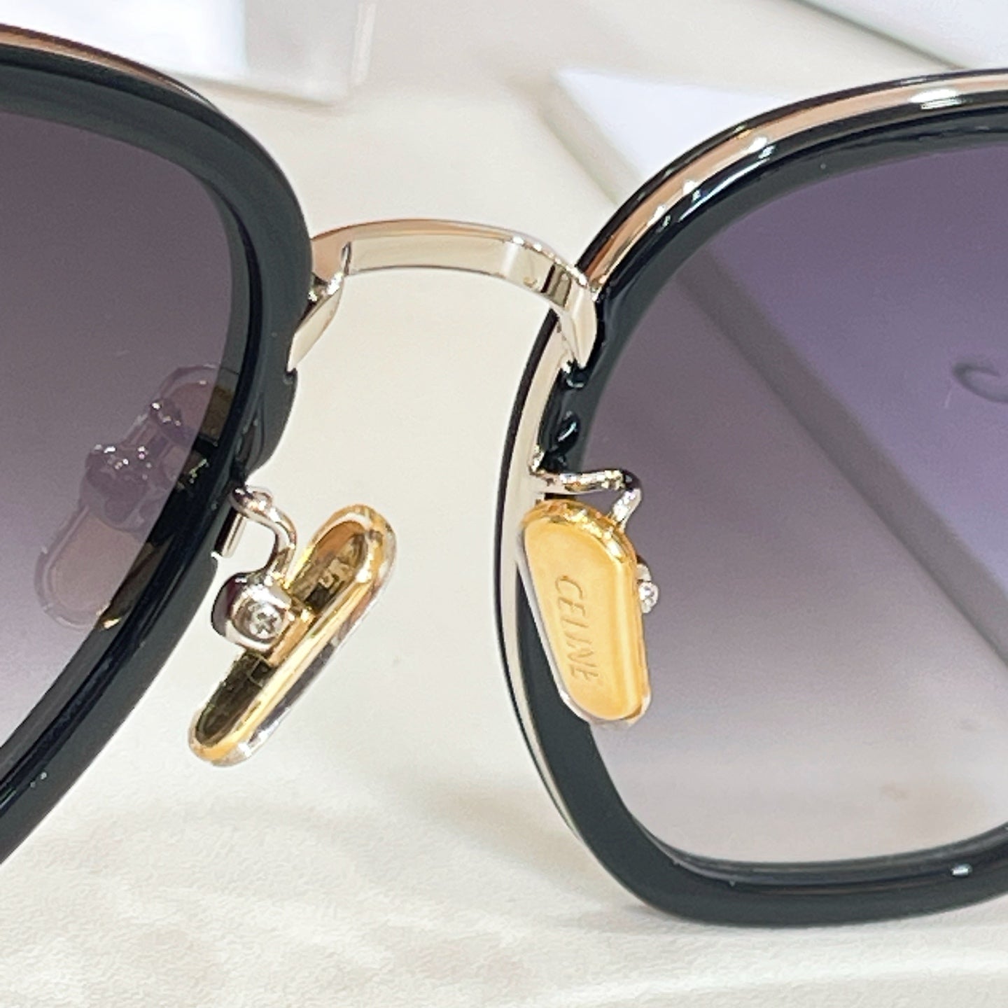 Sunglasses close-up: gold-tone hinge hardware and logo on temple