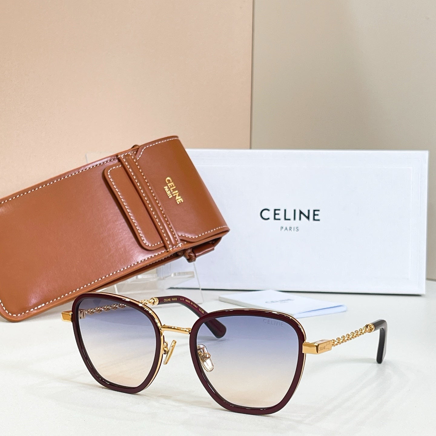 Burgundy red sunglasses with light lenses and gold chain temples