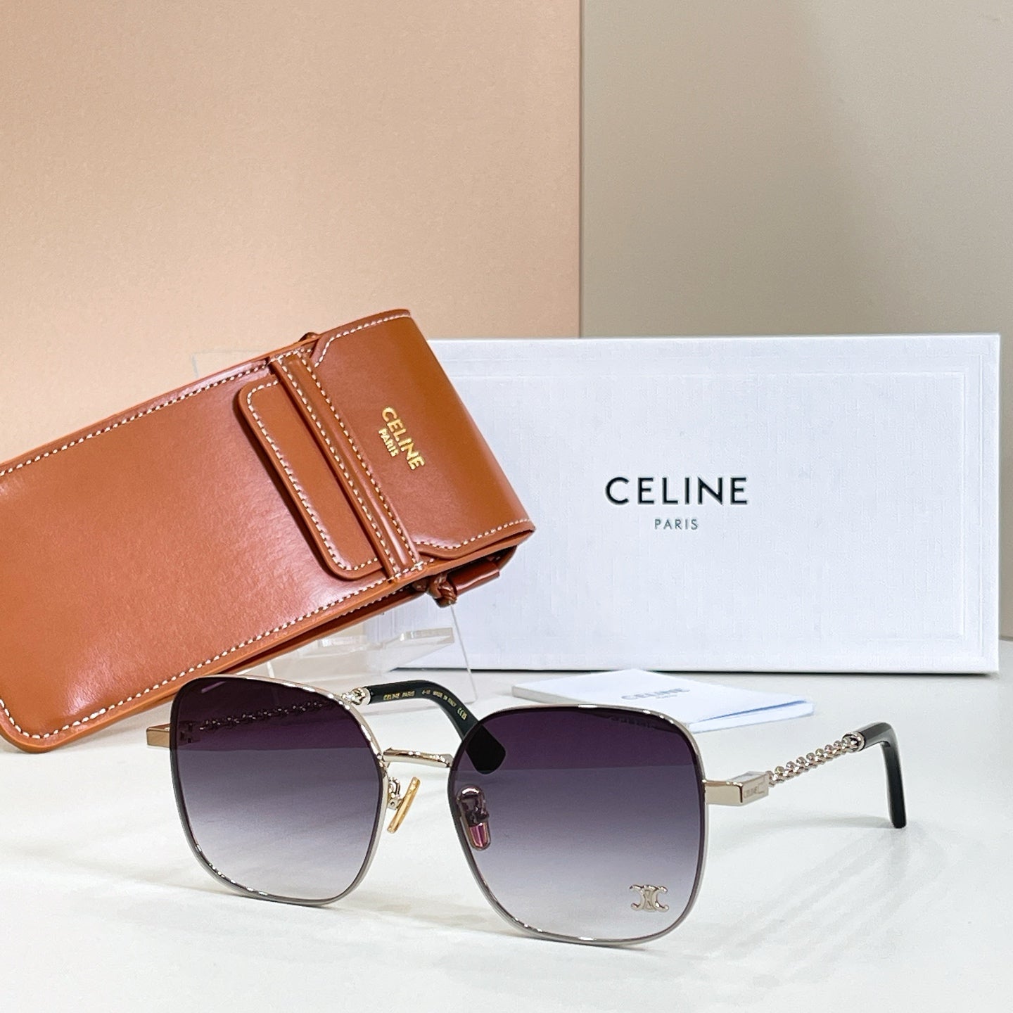 Sunglasses with round purple gradient lenses, gold-tone frame, and chain-link temple arms