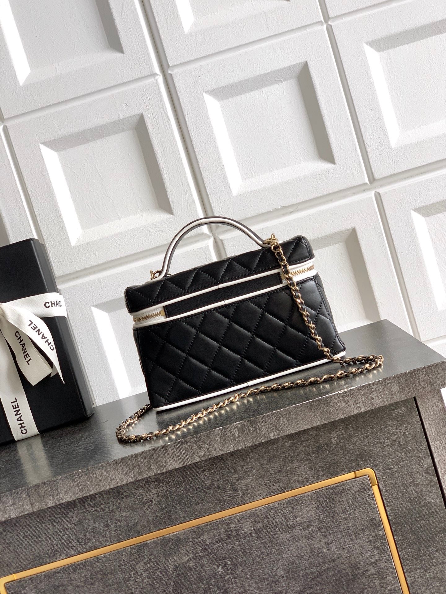 Black quilted mini handbag with chain strap and top handle, white trim accents