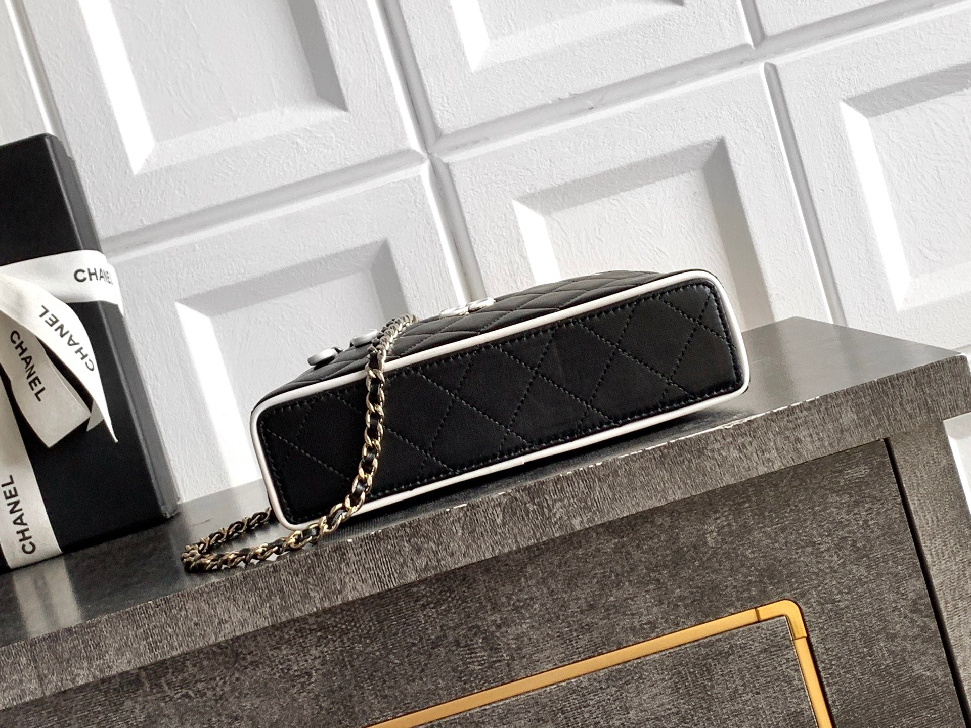 Black rectangular quilted clutch bag with chain strap and gold-tone hardware