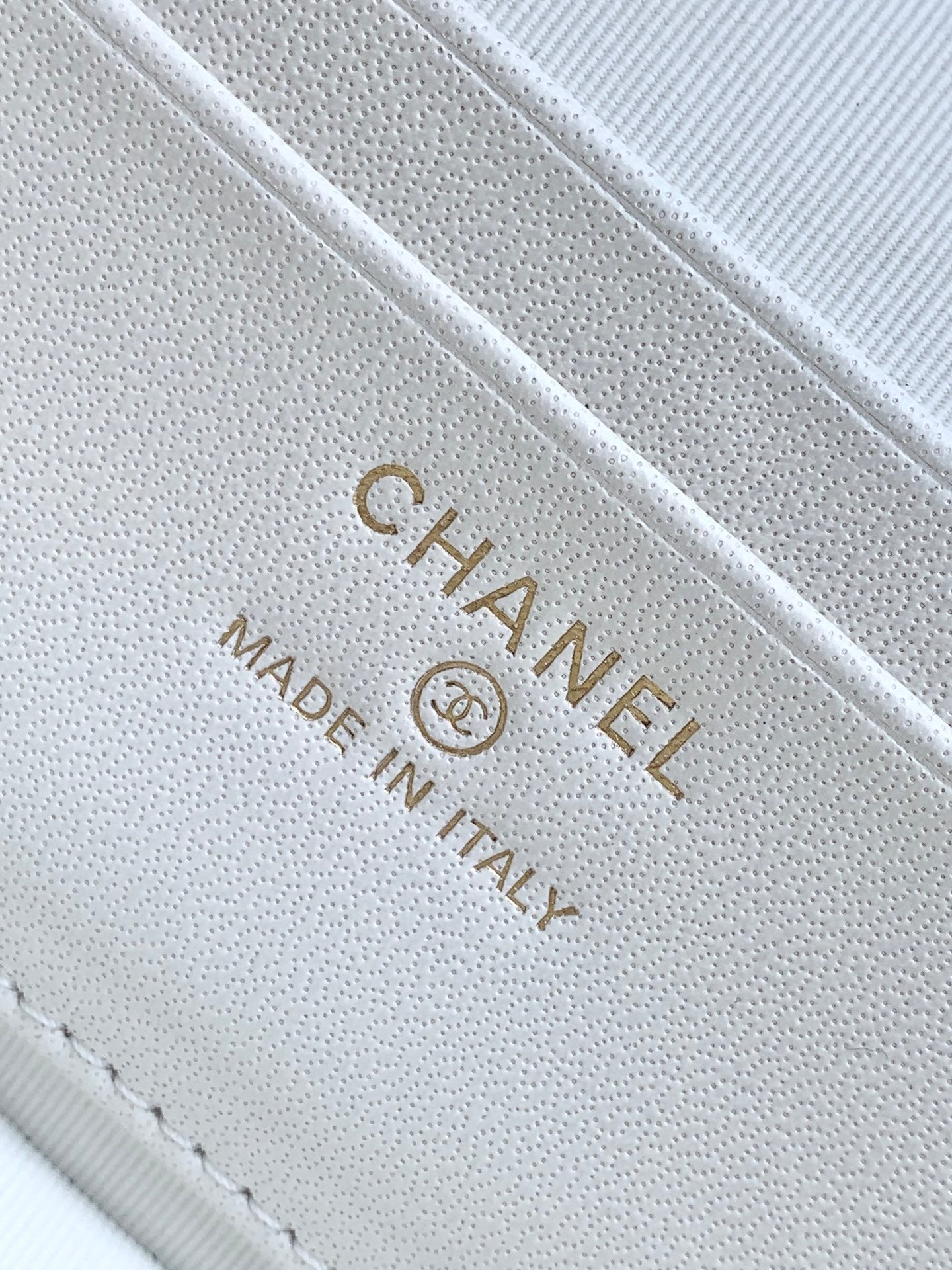 Chanel logo stamp on white quilted leather, text reads "Made in Italy"