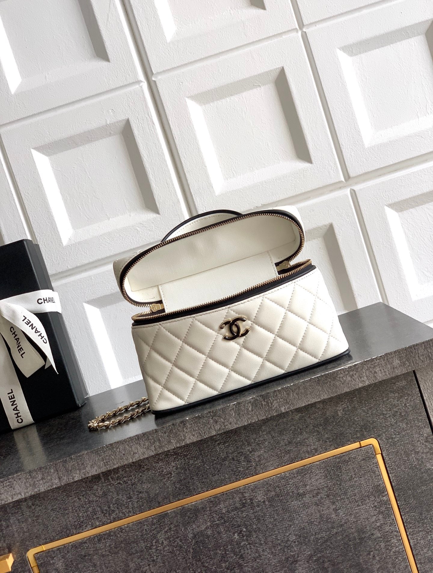 White quilted crossbody bag with top handle and chain strap, gold-tone emblem