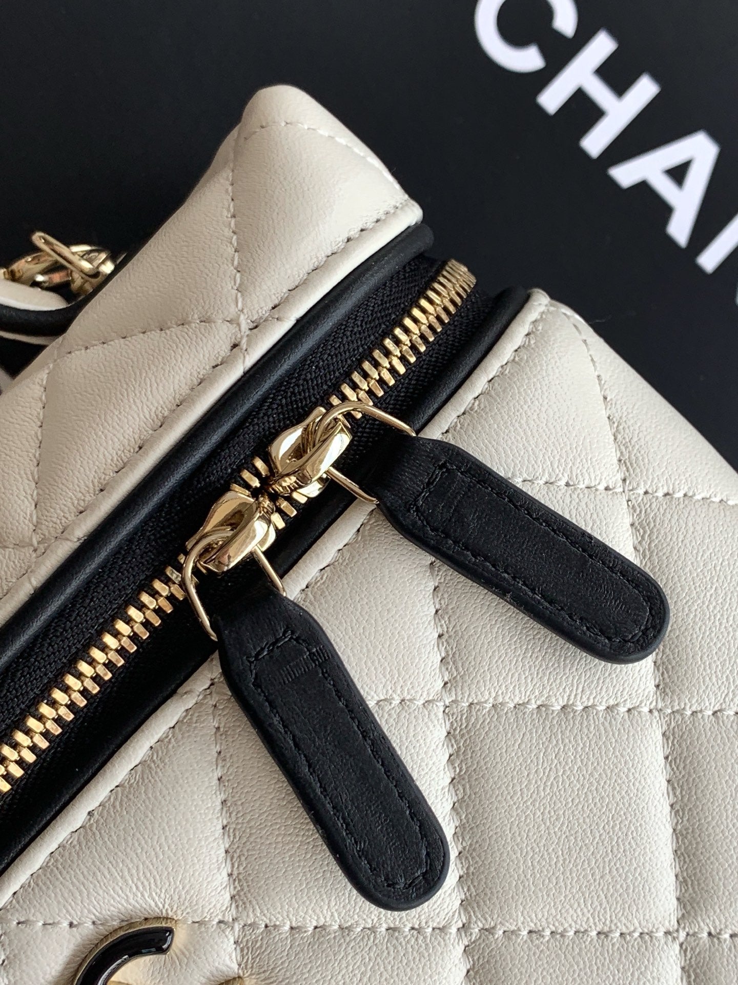 Quilted bag close-up showing black leather trim and gold zipper hardware