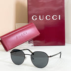 Round black sunglasses with dark lenses and metal temples with logo detail