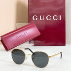 Round gold sunglasses with dark lenses and metal temples with striped detail