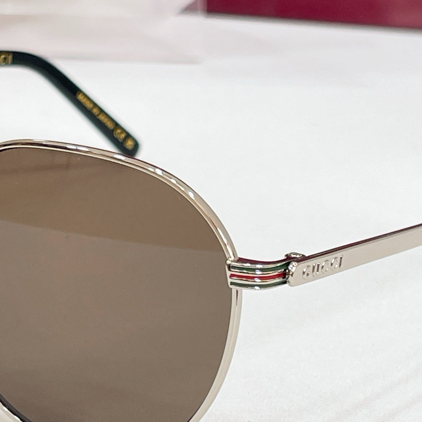 Close-up of round sunglasses temple with striped accent and brand mark