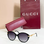 Black round sunglasses with gold-tone accents and purple-tinted lenses