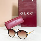 Black round sunglasses with gold-tone accents and brown-tinted lenses