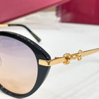 Black sunglasses temple with gold-tone bar accents and tinted lens edge