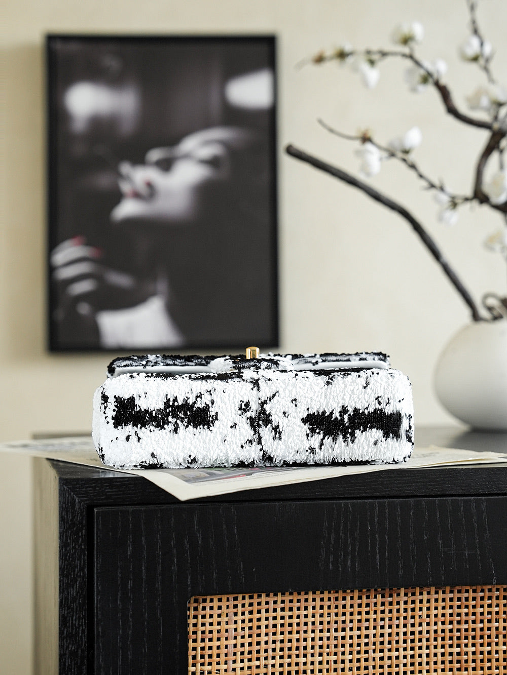 Black-and-white sequin shoulder bag lying on box, gold chain visible