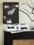 Black-and-white sequin shoulder bag lying on box, gold chain visible