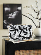 Black-and-white sequin shoulder bag with gold chain and front logo flap